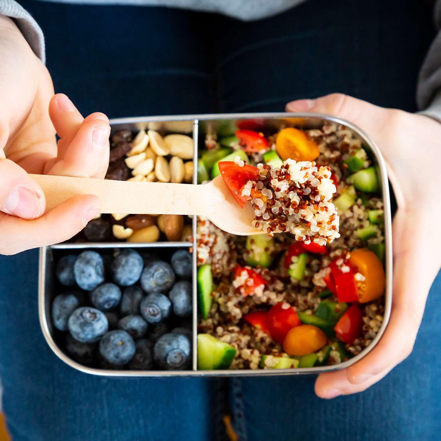 Lunchbox with quinoa salad with tomato and cucumber, blue berry and trail mix