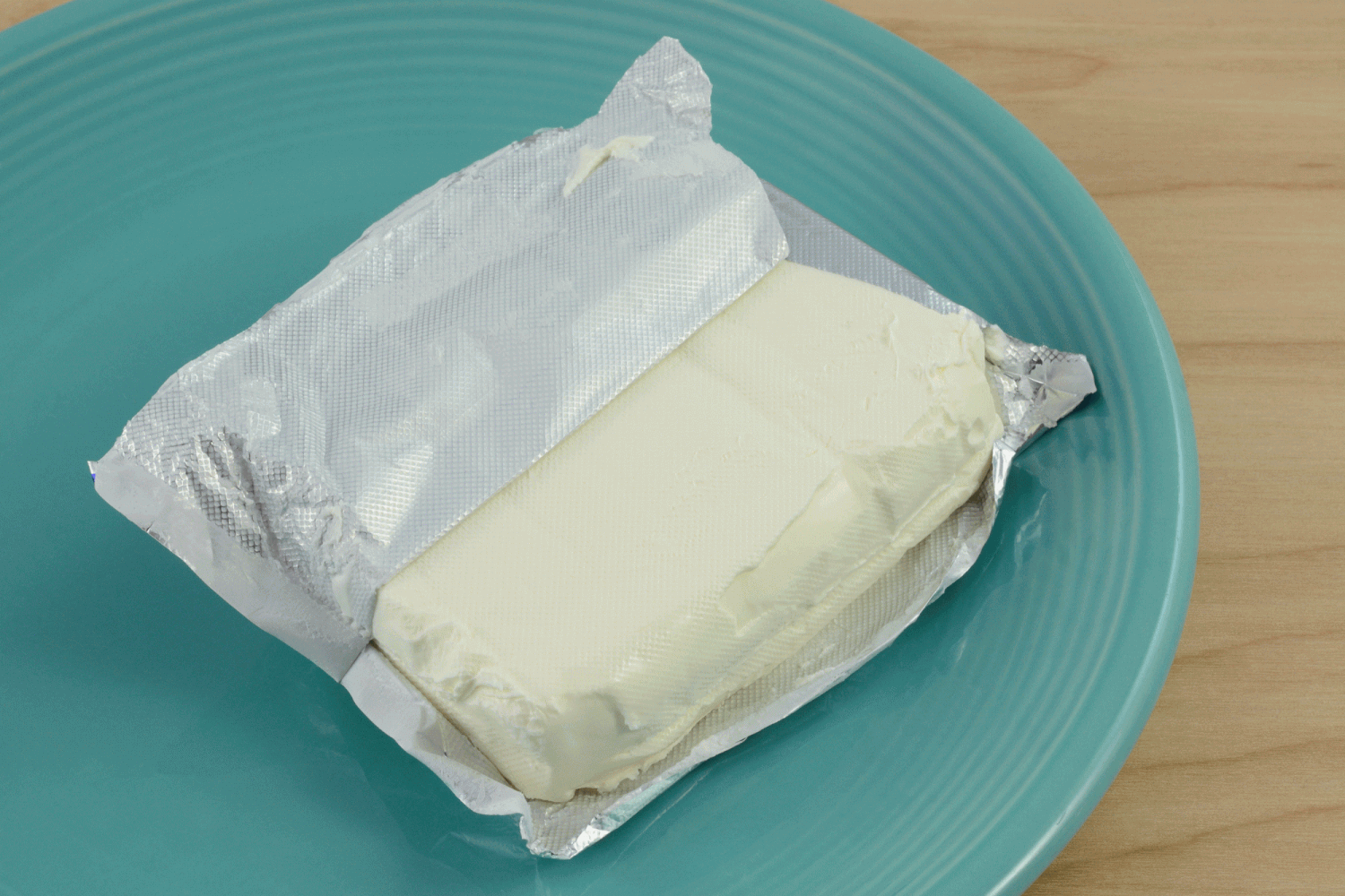 Block of cream cheese on blue plate