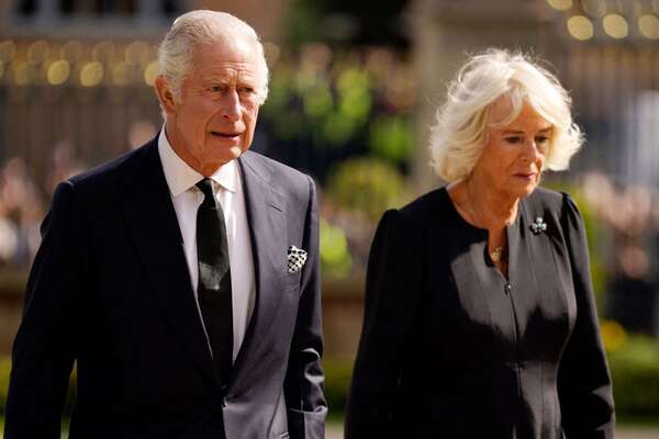 Britain's King Charles III and Britain's Camilla, Queen Consort look at flowers and tributes left in honour of his late mother Queen Elizabeth II, as they arrive at Hillsborough Castle in Belfast on September 13, 2022, during his visit to Northern Ireland. - King Charles III on Tuesday travelled to Belfast where he is set to receive tributes from pro-UK parties and the respectful sympathies of nationalists who nevertheless can see reunification with Ireland drawing closer. (Photo by Niall Carson / POOL / AFP) (Photo by NIALL CARSON/POOL/AFP via Getty Images)