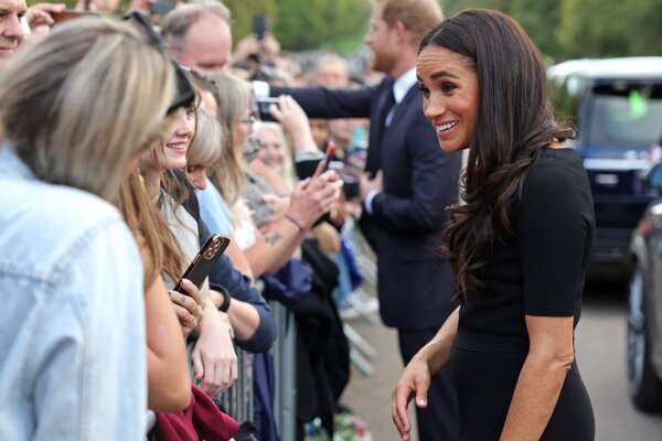 WINDSOR, ENGLAND - SEPTEMBER 10: Meghan Duchess of Sussex speaks with well-wishers at Windsor Castle on September 10, 2022 in Windsor, England. Crowds have gathered and tributes left at the gates of Windsor Castle to Queen Elizabeth II, who died at Balmoral Castle on 8 September, 2022. (Photo by Chris Jackson - WPA Pool/Getty Images)