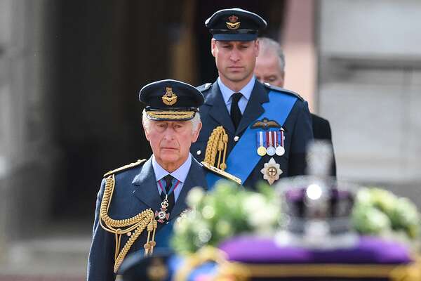 King Charles III and Britain's Prince William, Prince of Wales walk behind the coffin of Queen Elizabeth II, adorned with a Royal Standard and the Imperial State Crown