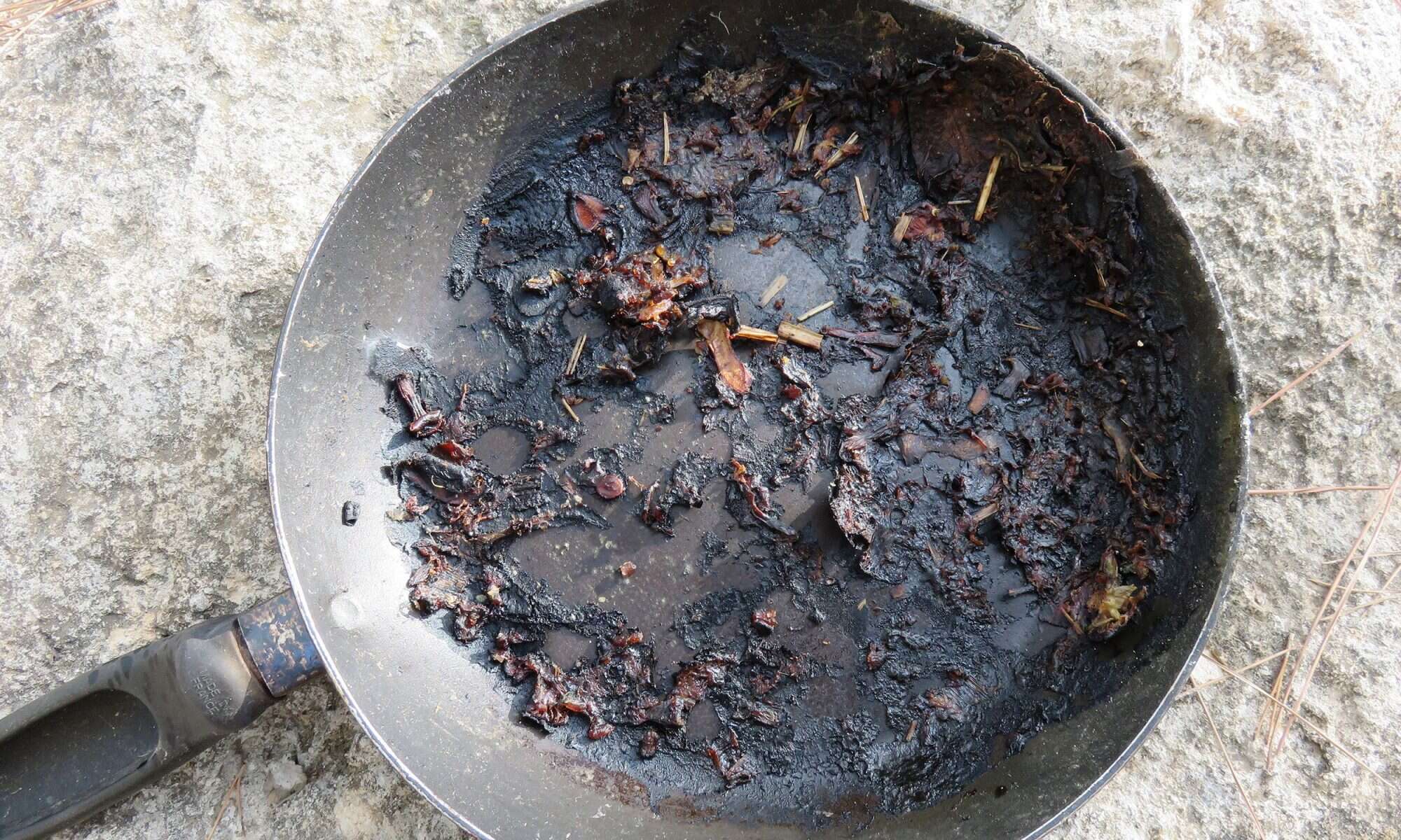 A spatula for stirring food picks off burnt food in a pan. Poor