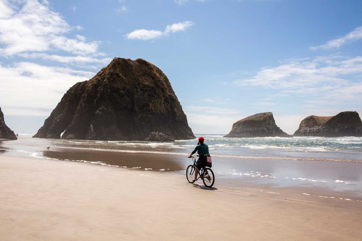 Woman riding bicycle on Cannon Beach in Oregon