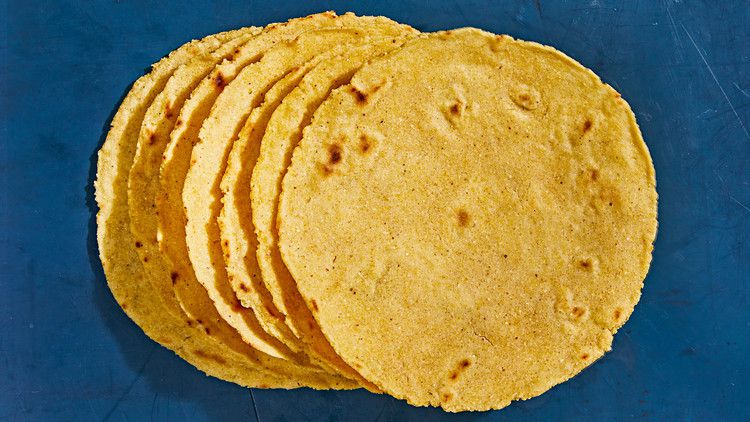 homemade corn tortillas stacked against blue background