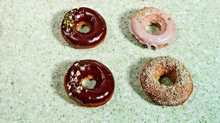 rows of doughnuts on green countertop with vegan and pumpkin flavors