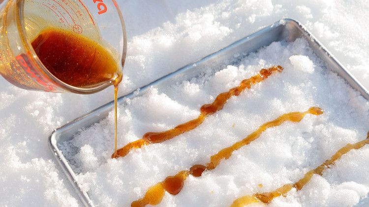 making maple taffy by pouring syrup on snow