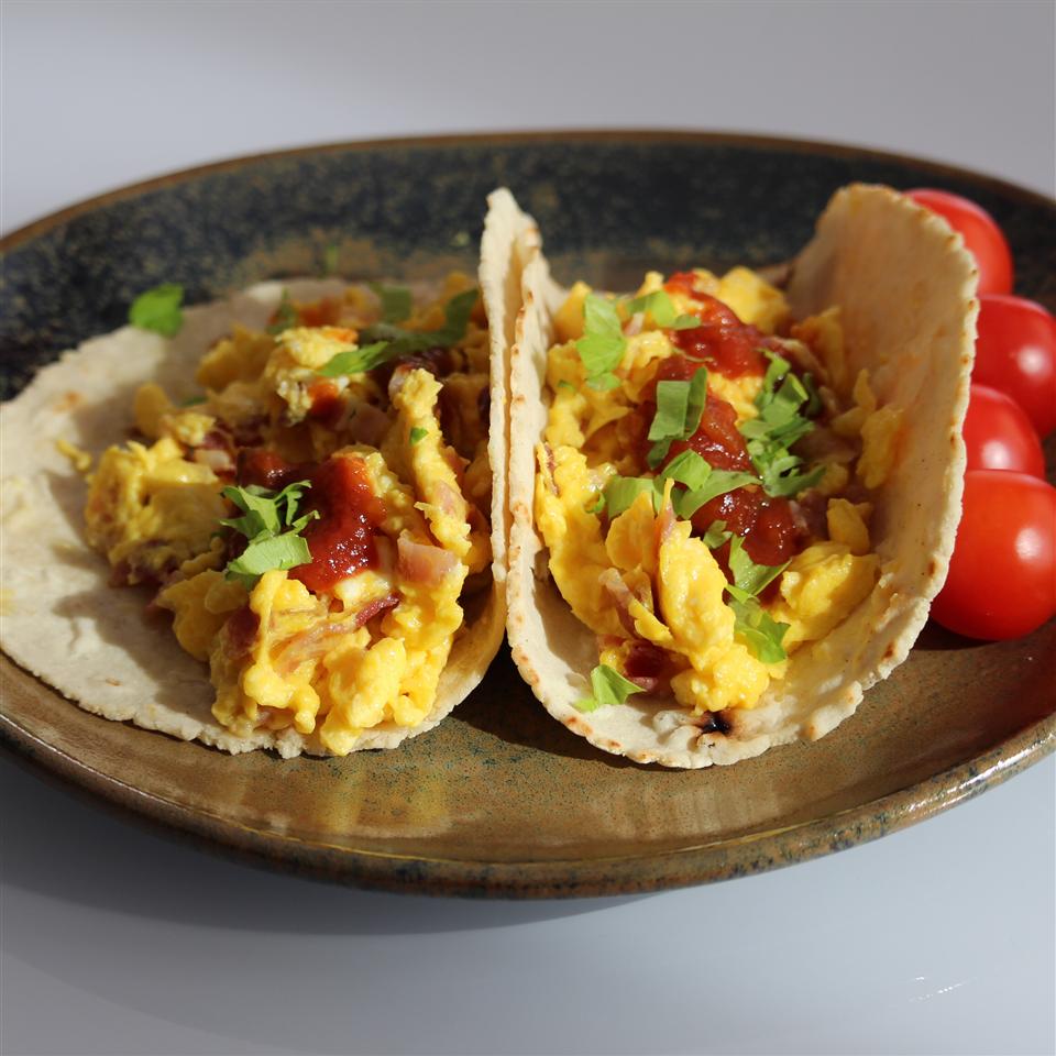 <p>With fluffy scrambled eggs and salty, crispy crumbled bacon, these tacos bridge the gap between breakfast and brunch beautifully. Without a juicy sauce, these handheld appetizers are easy for guests to hold, and they won't have to worry about dripping or dropping anything onto their beautiful shower attire. Set up a bar of toppings, and let each guest make their own tacos.</p>
                          