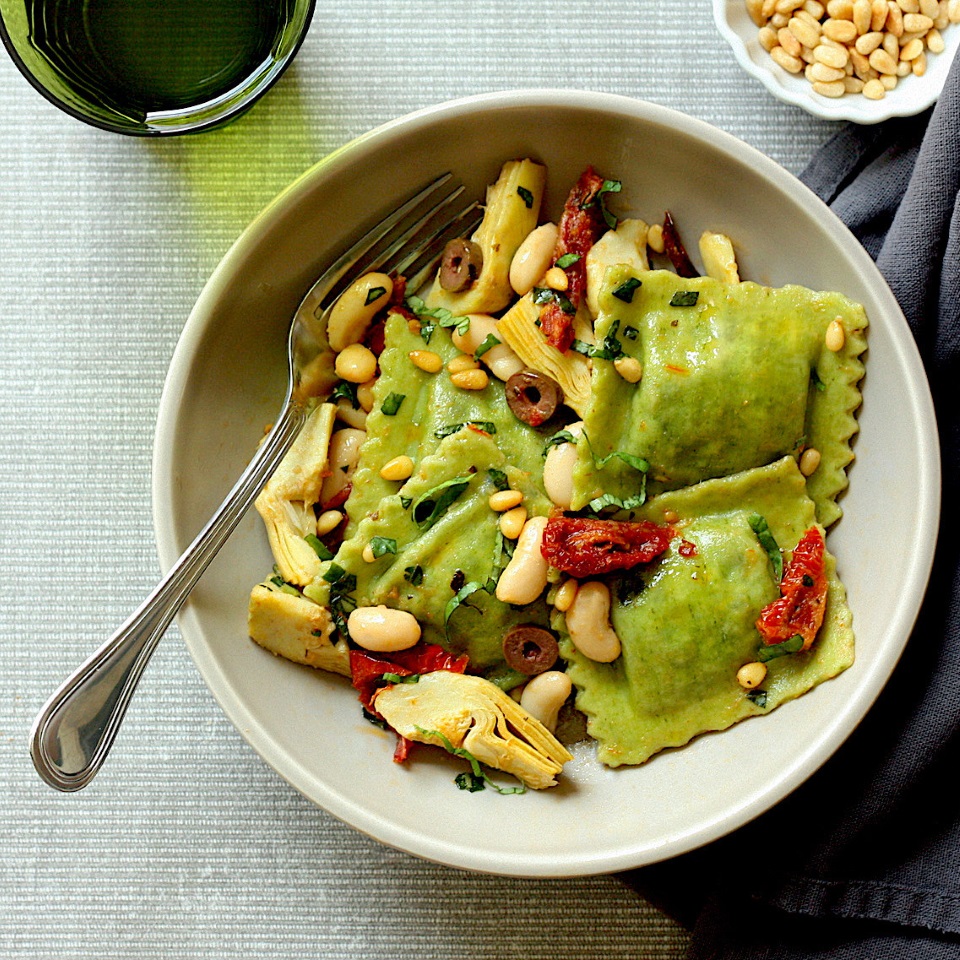 <p>Store-bought spinach ravioli and a handful of basic pantry items are all you need to get a healthy dinner on the table in 15 minutes. Ingredients like oil-packed sun-dried tomatoes, briny Kalamata olives and toasty pine nuts help to build big flavor fast. If you can't find frozen artichokes, swap in a 15-ounce can (just be sure to drain and rinse them well).</p>
                          