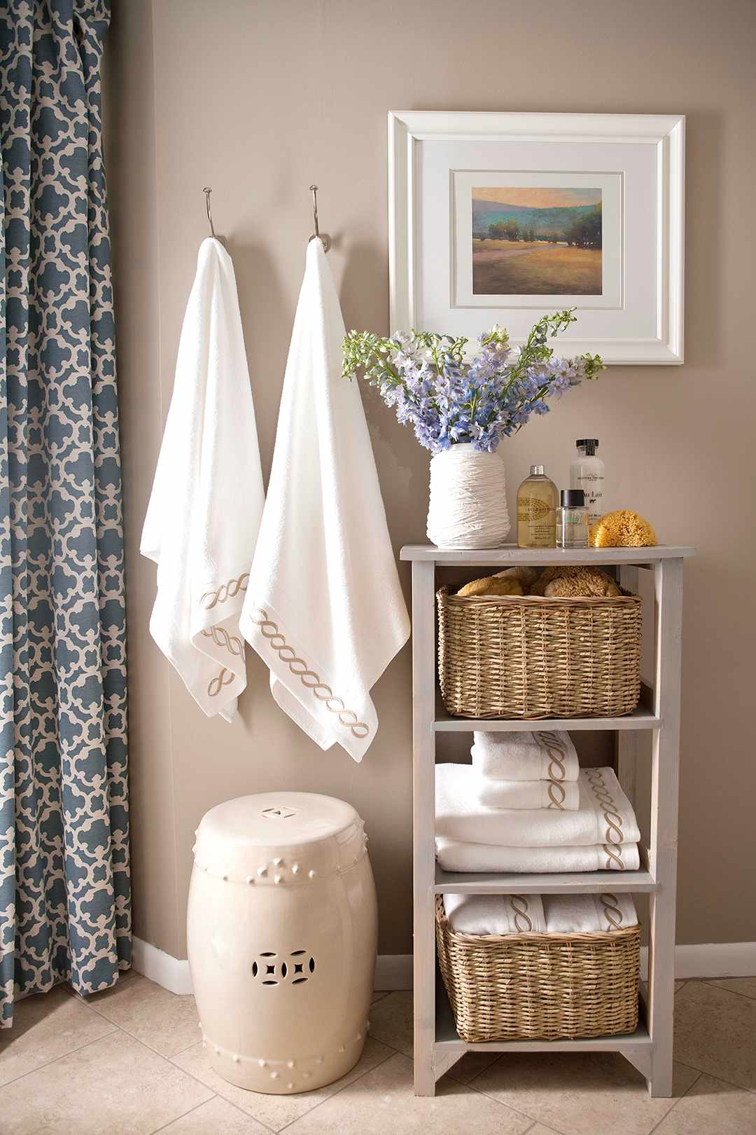 soft taupe bathroom with white towels hanging and folded on taupe shelf