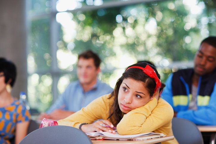 Student resting head on desk in classroom
