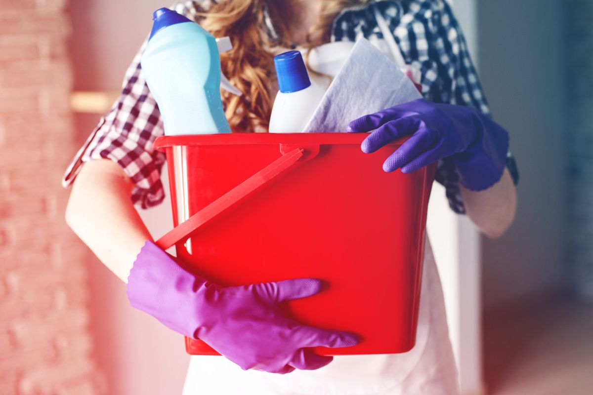 Close-up of woman's hands holding red bucket full of cleaners