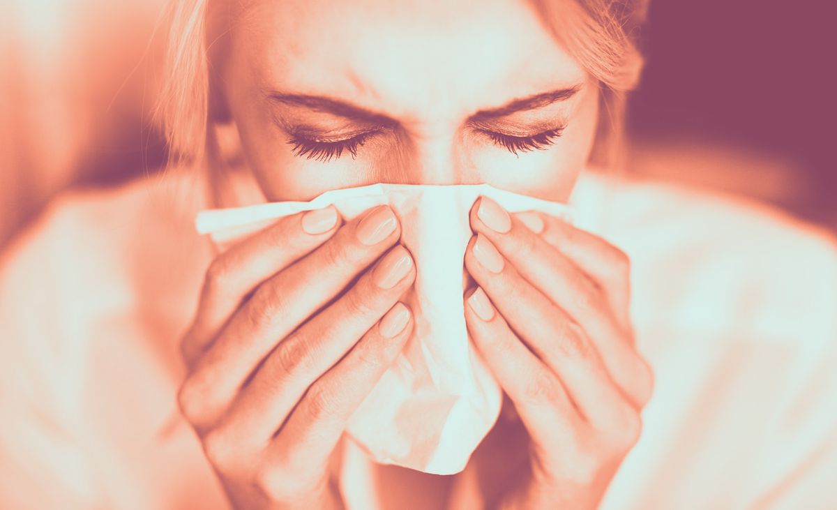 woman sneezing in tissue blowing nose flue cold nose runny-nose