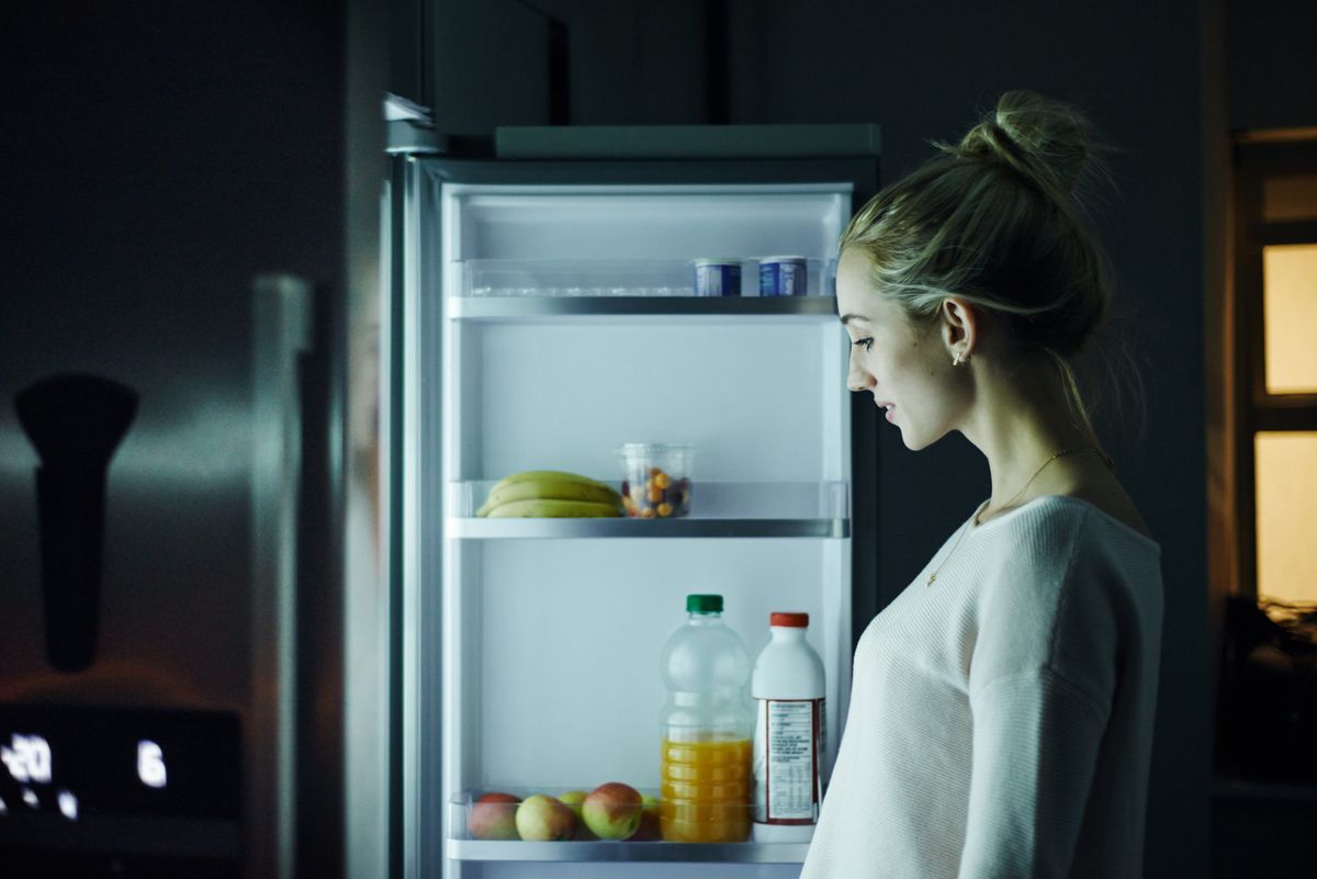 Woman looking at fridge at night