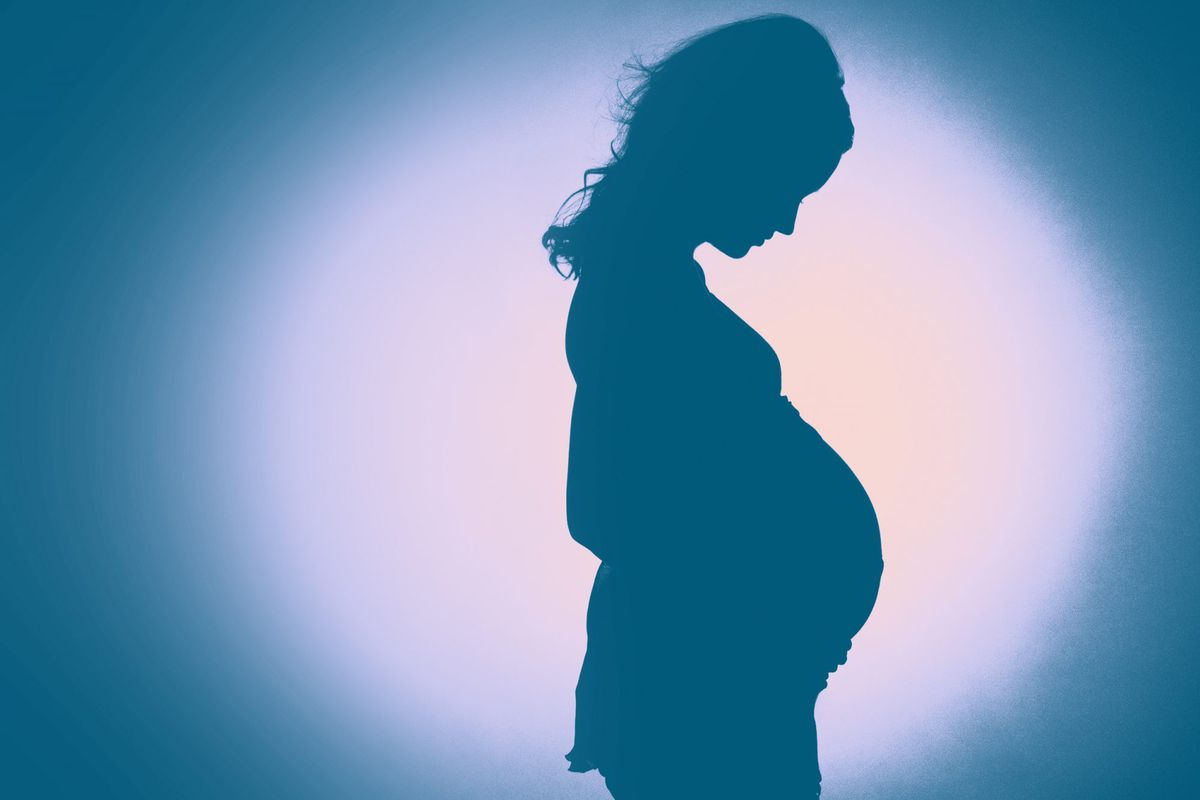 silhouette of pregnant young lady in studio. green background
