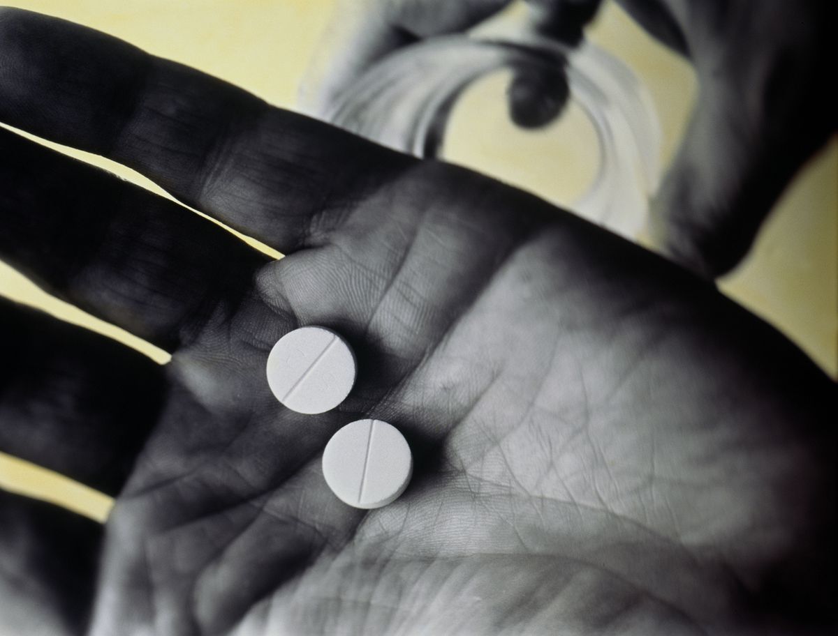 Man's hand holding two white tablets, close-up. Hydroxychloroquine at Home