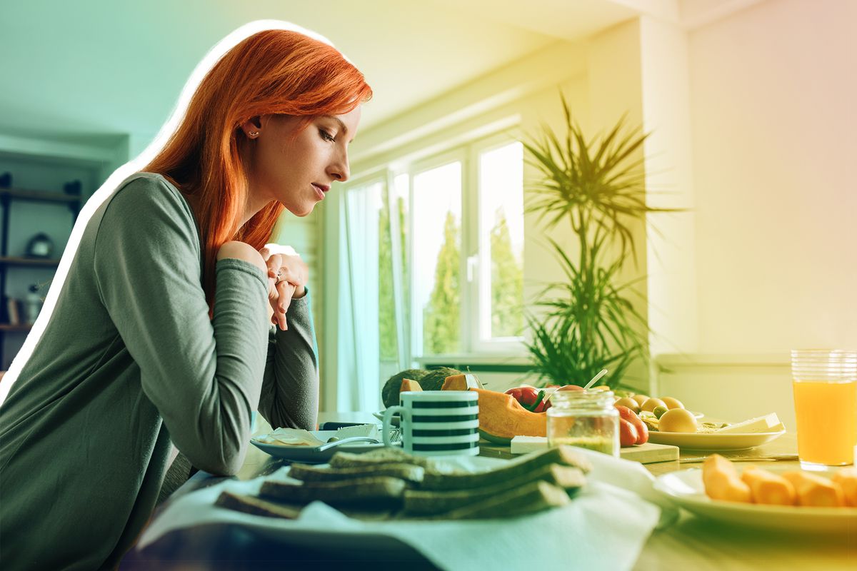 Lonely redhead woman sitting at dining table and thinking of something.