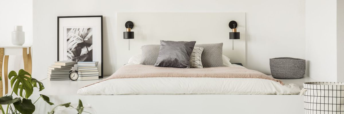 乳胶床垫，小灯放在白色床头简单的床垫床与枕头在卧室内部与书籍，时钟和海报