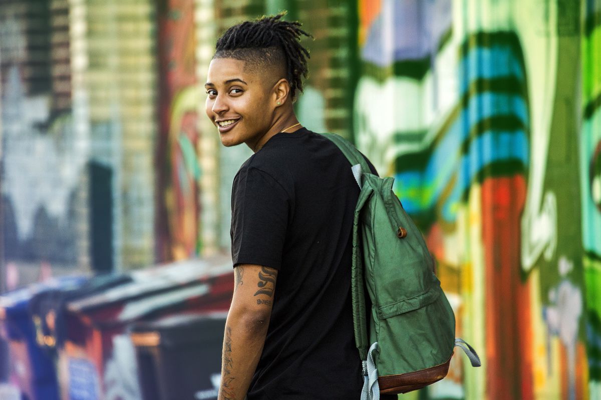 genderqueer, Portrait of smiling androgynous Mixed Race woman near on graffiti wall