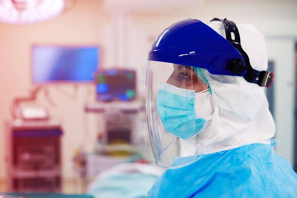Close up view of a docotr wearing surgical mask and a face shield.