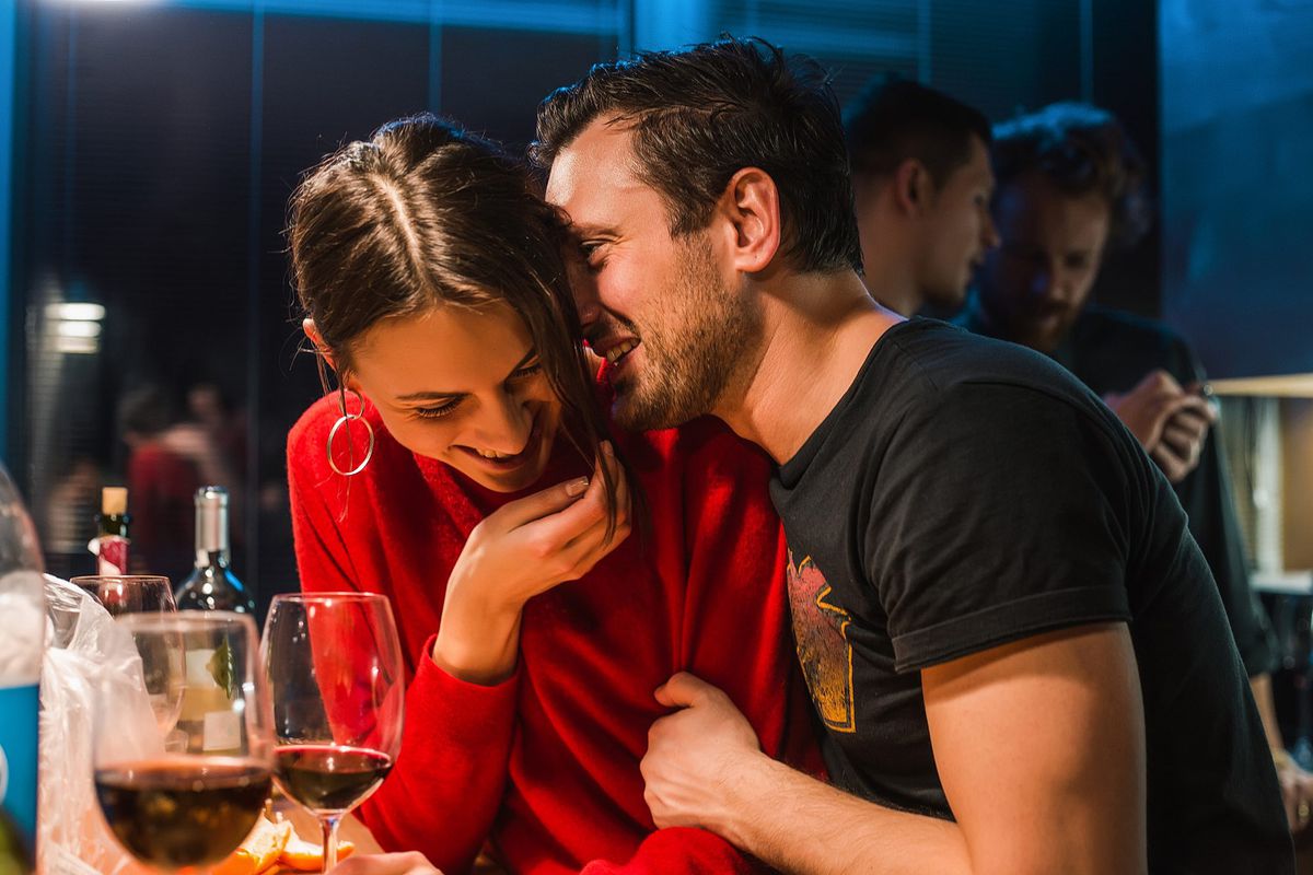 Couple drinking wine at party in apartment