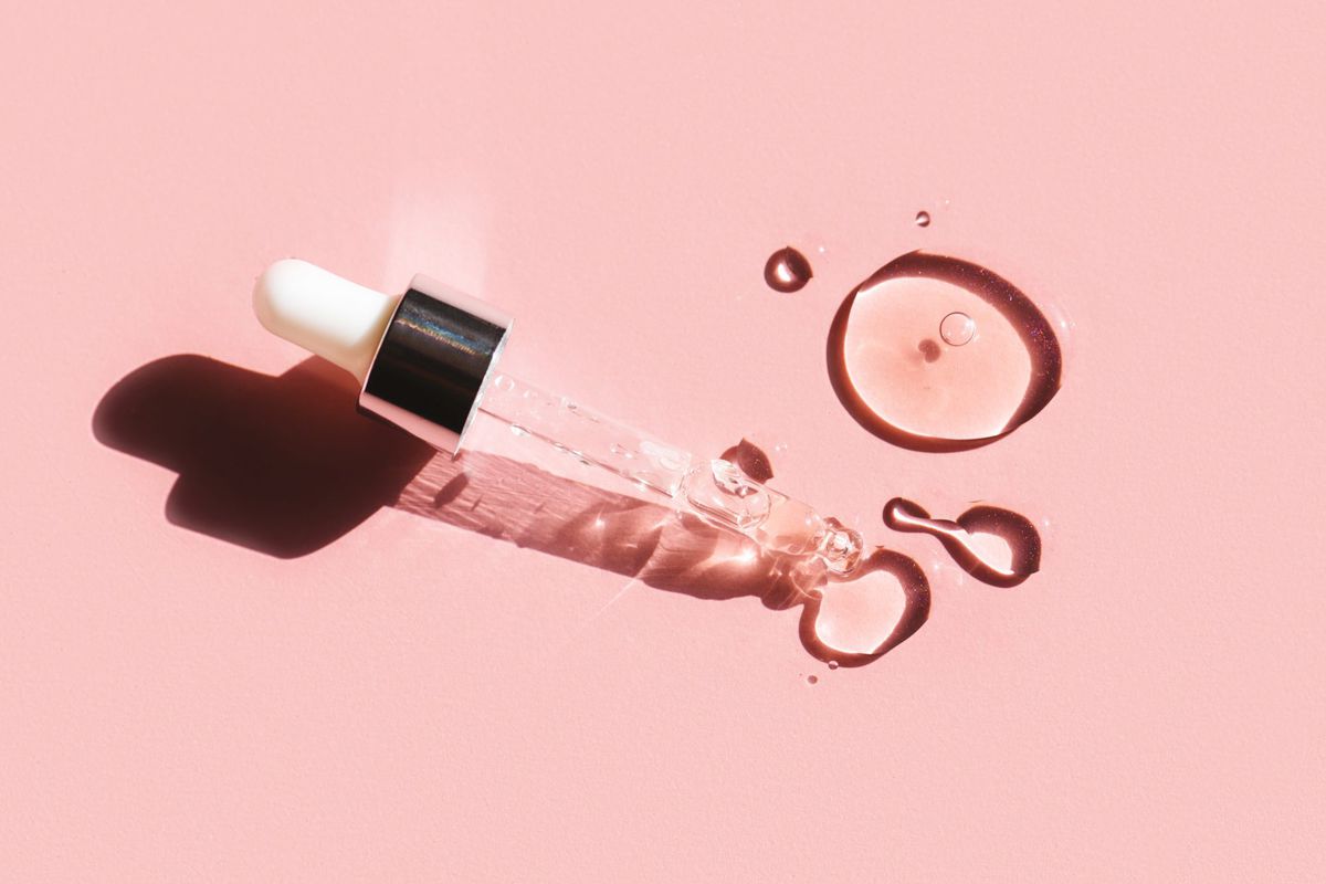 Over 12,000 People Adore This Plumping Anti-Aging Serum That Makes You Look '5 Years Younger' , Flat lay. Liquid gel or serum drop with pipette on pink background in macro.