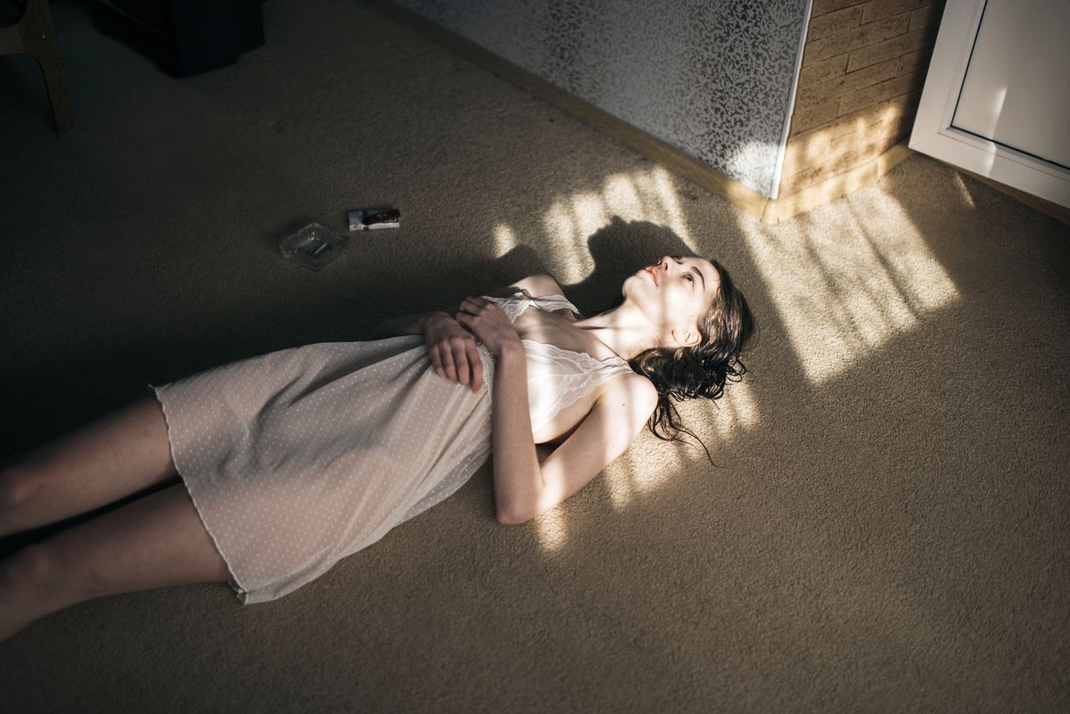 anhedonia , Caucasian woman laying in sun spot on floor