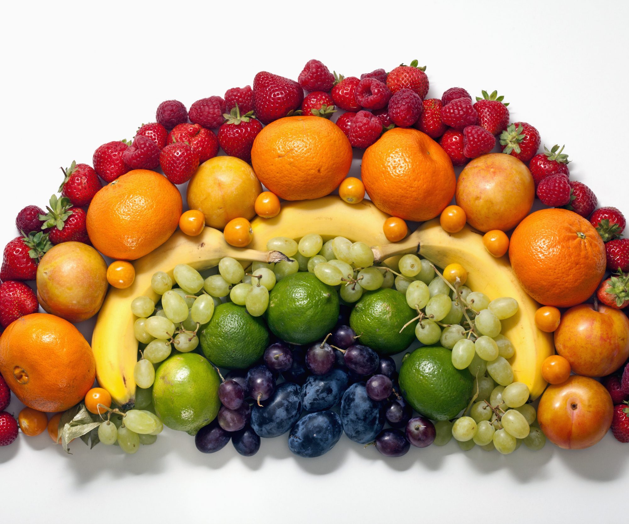 Various fruits arranged into the shape of a rainbow