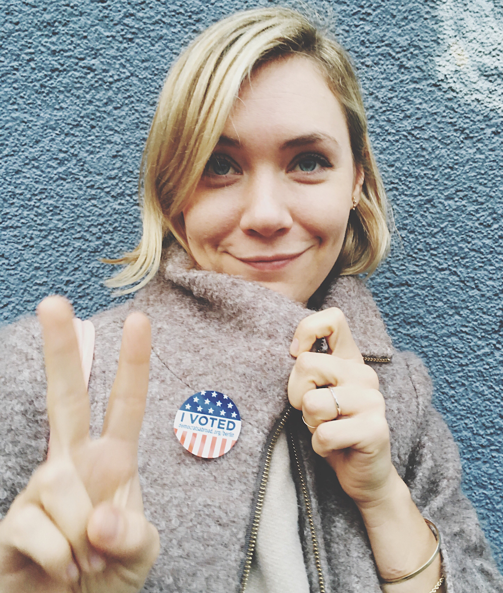Smiling Beautiful Woman Wearing Campaign Button Gesturing Peace Sign