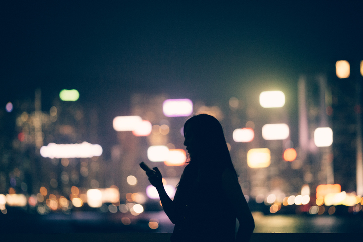 Silhouette of office lady using smartphone in city