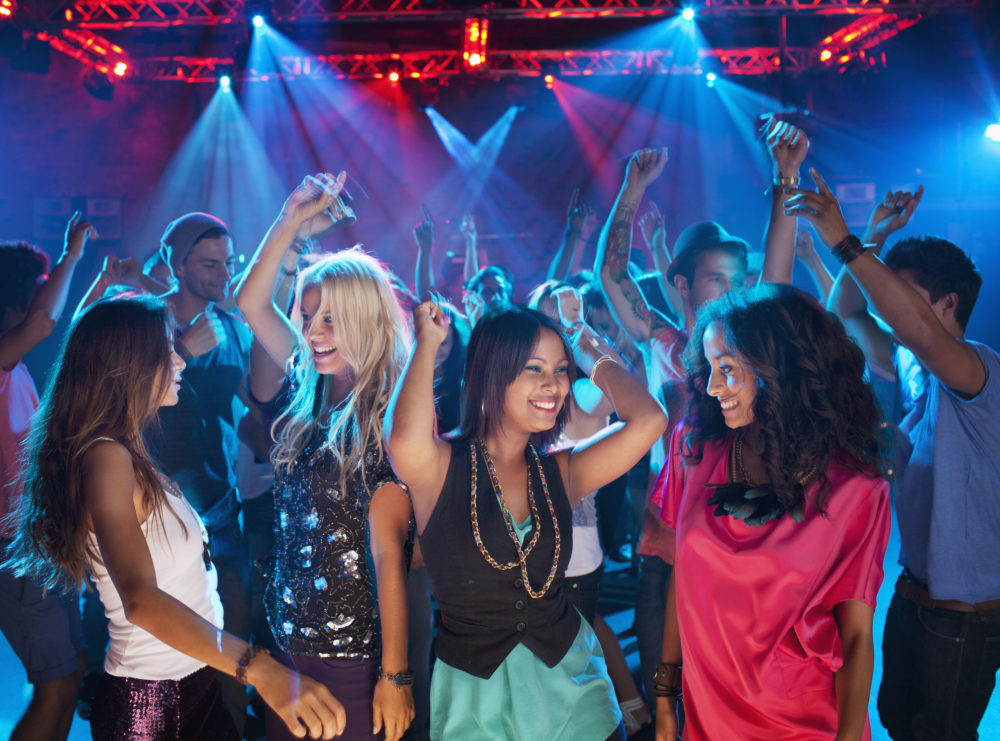 Smiling friends dancing on dance floor of nightclub