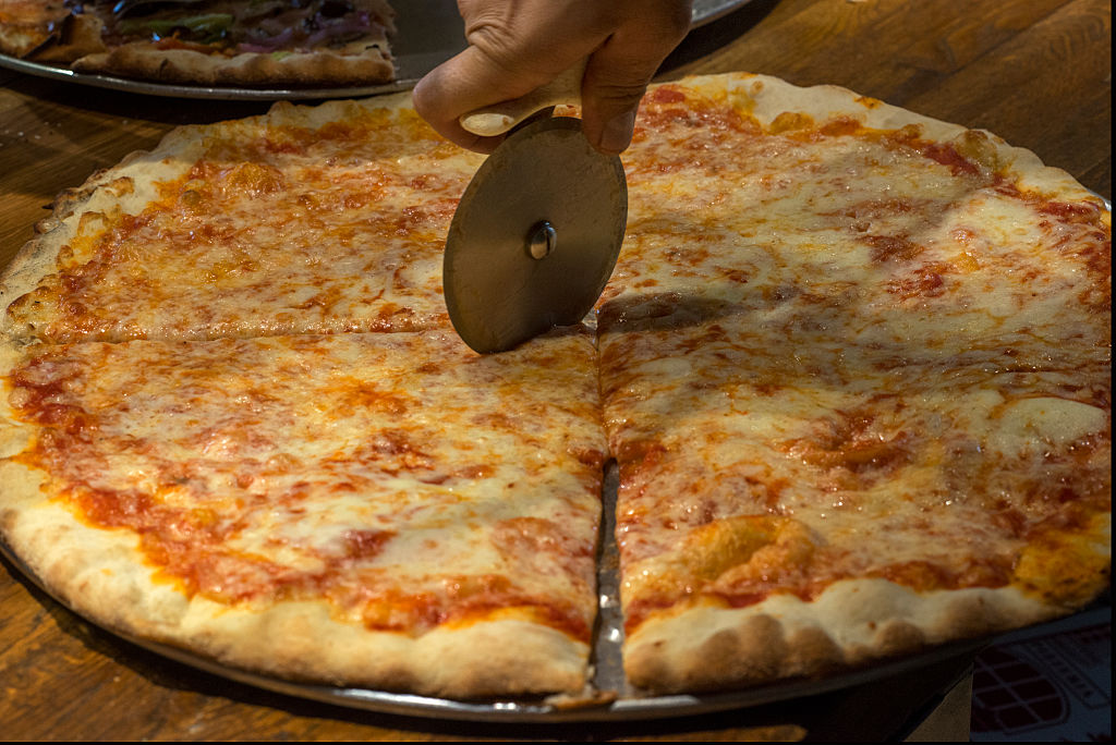 a pizza pie being sliced with a pizza cutter