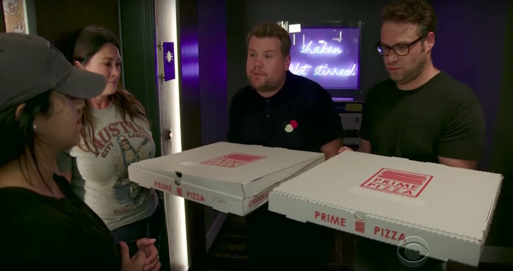 James Corden and Seth Rogen offering two pizza boxes