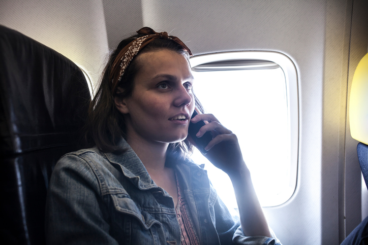 Woman using mobile phone inside airplane