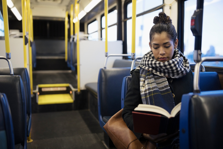 girl reading book on bus
