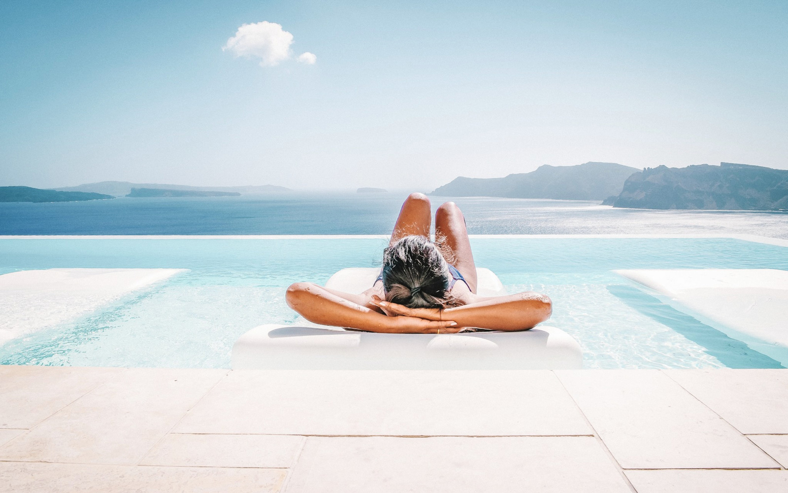 Woman Relaxing On Pool Raft Floating On Swimming Pool Against Sky