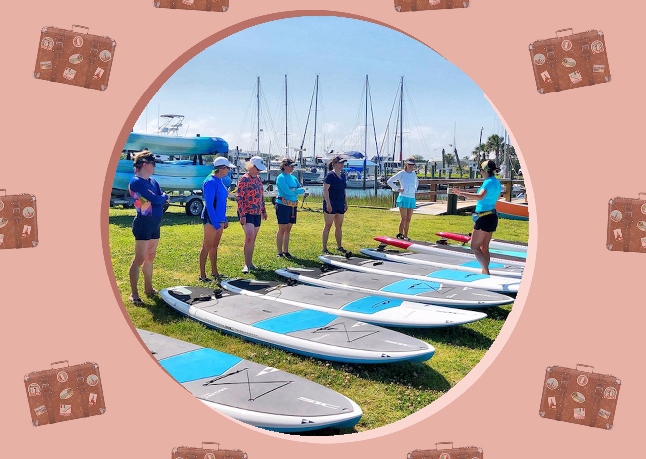 A group of women standing next to their paddle boards on land in the Crystal Cove