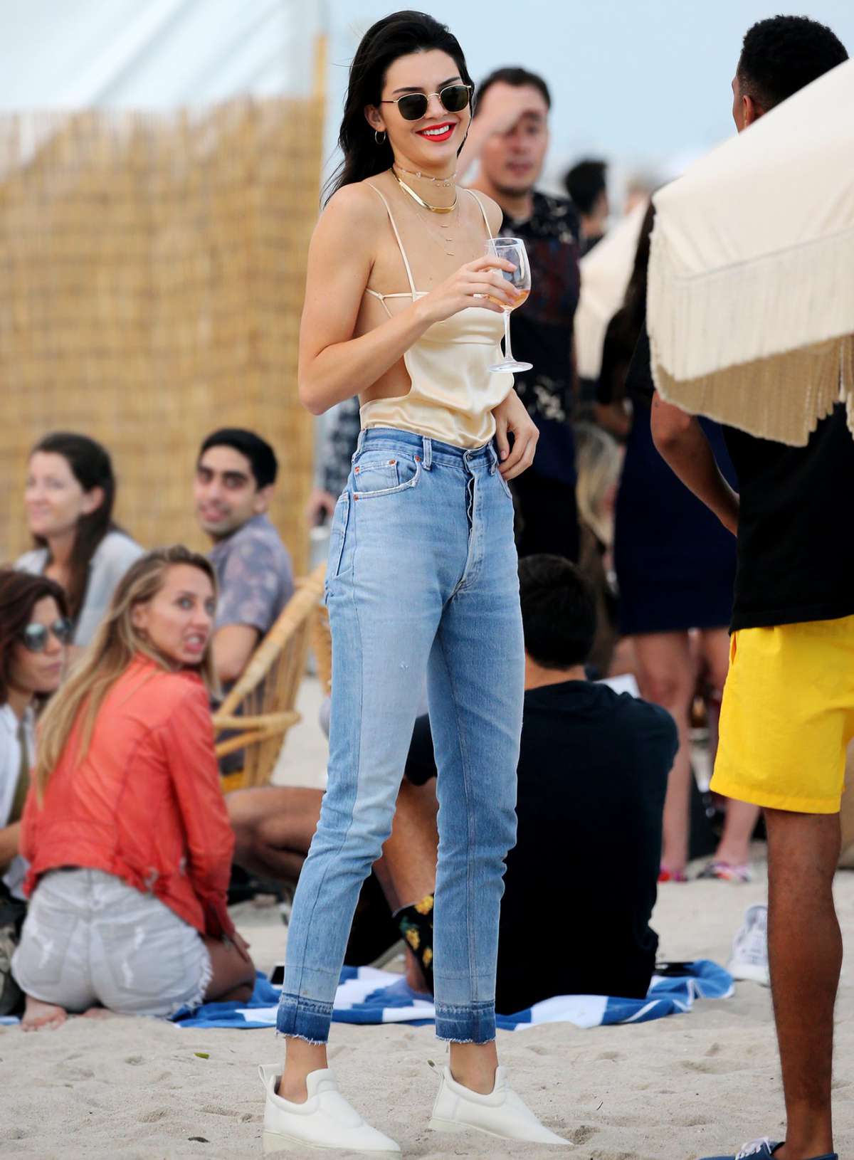 December 4, 2016: Kendall Jenner wears a revealing strappy top and jeans as she enjoys a glass of wine on the beach in Miami. Mandatory Credit: INSTARimages