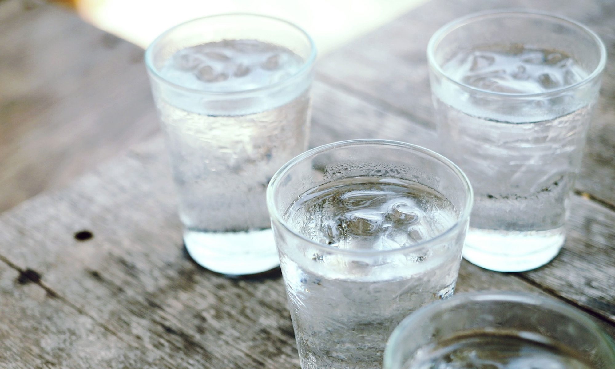 Four glasses of ice cold water on a wooden background