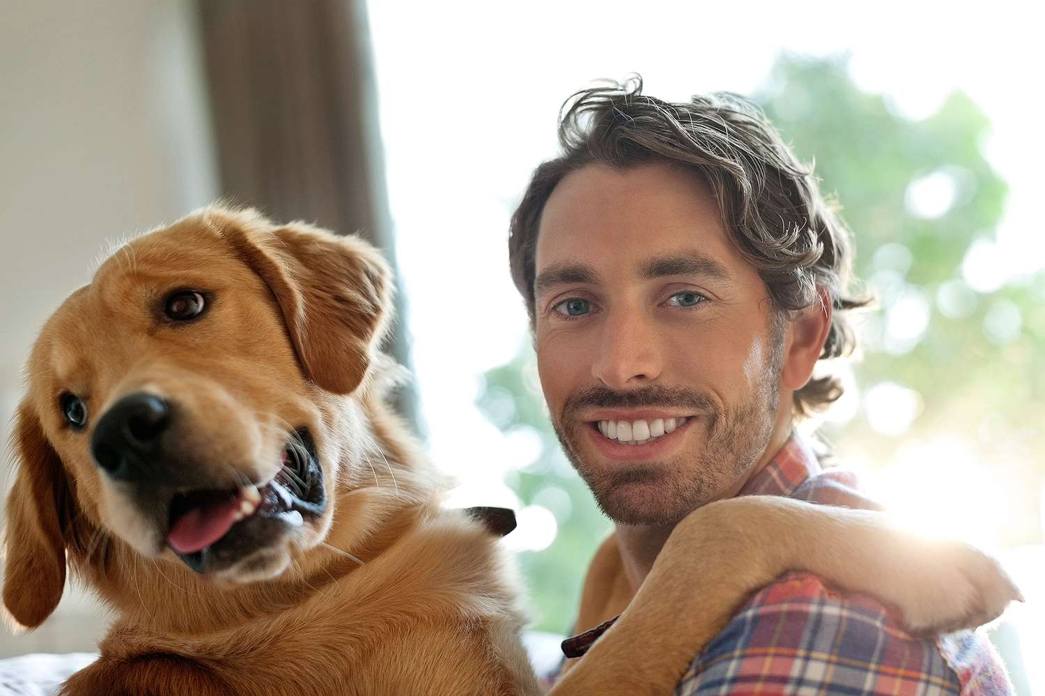 Smiling man petting dog indoors