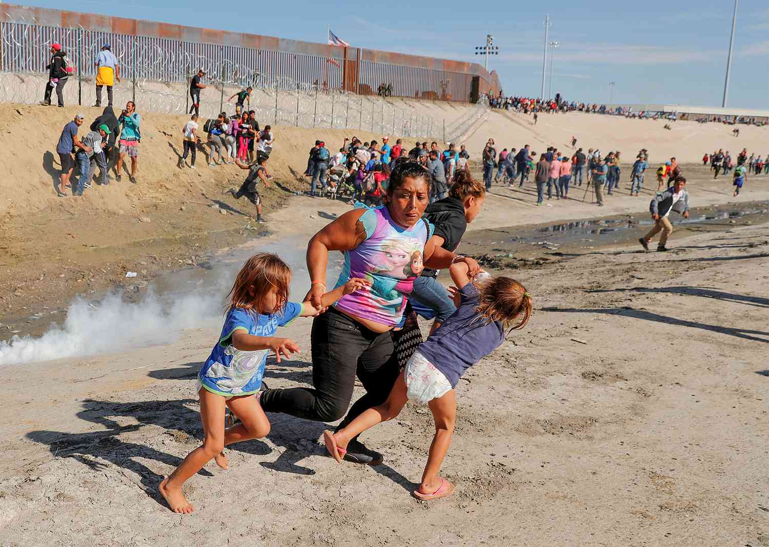 A migrant family, part of a caravan of thousands traveling from Central America en route to the United States, run away from tear gas in front of the border wall between the U.S and Mexico in Tijuana