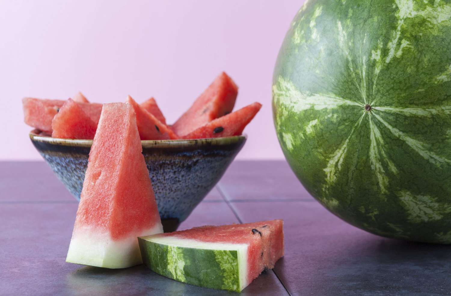 Close-Up Of Watermelon On Table Against Purple Background