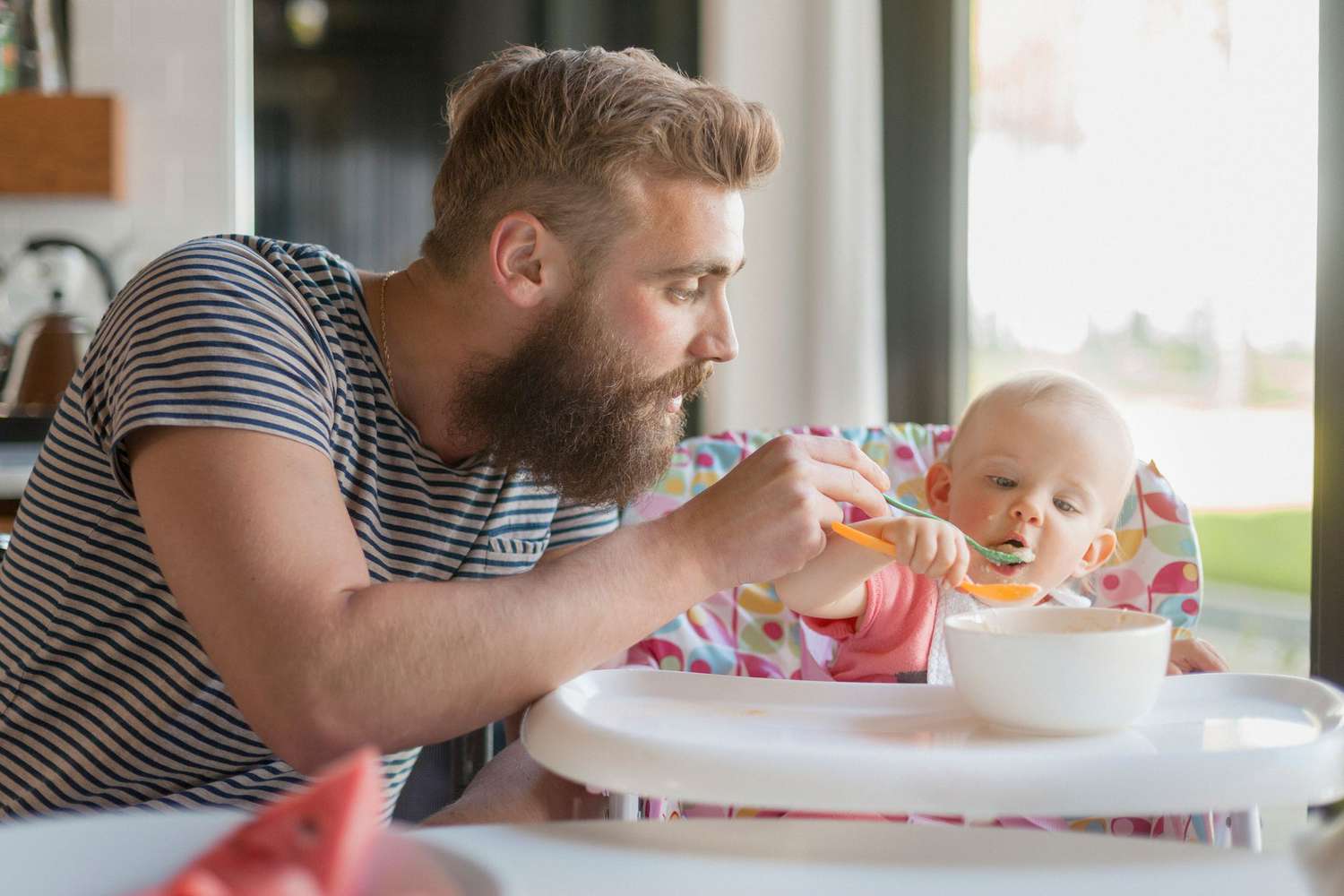 Father feeding baby girl (12-23 months) on high chair