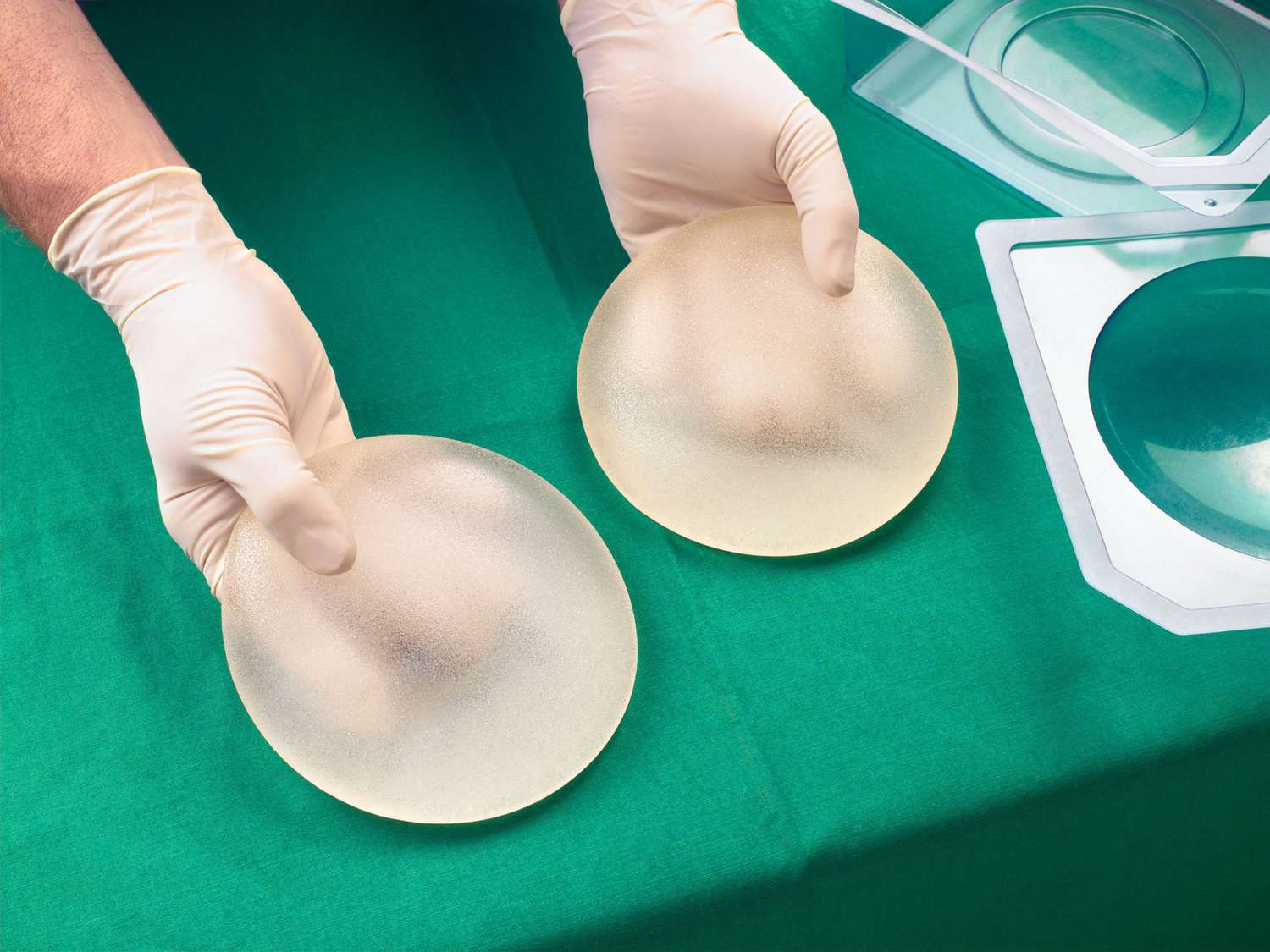 Surgeon holding silicone breast implants, close-up, elevated view