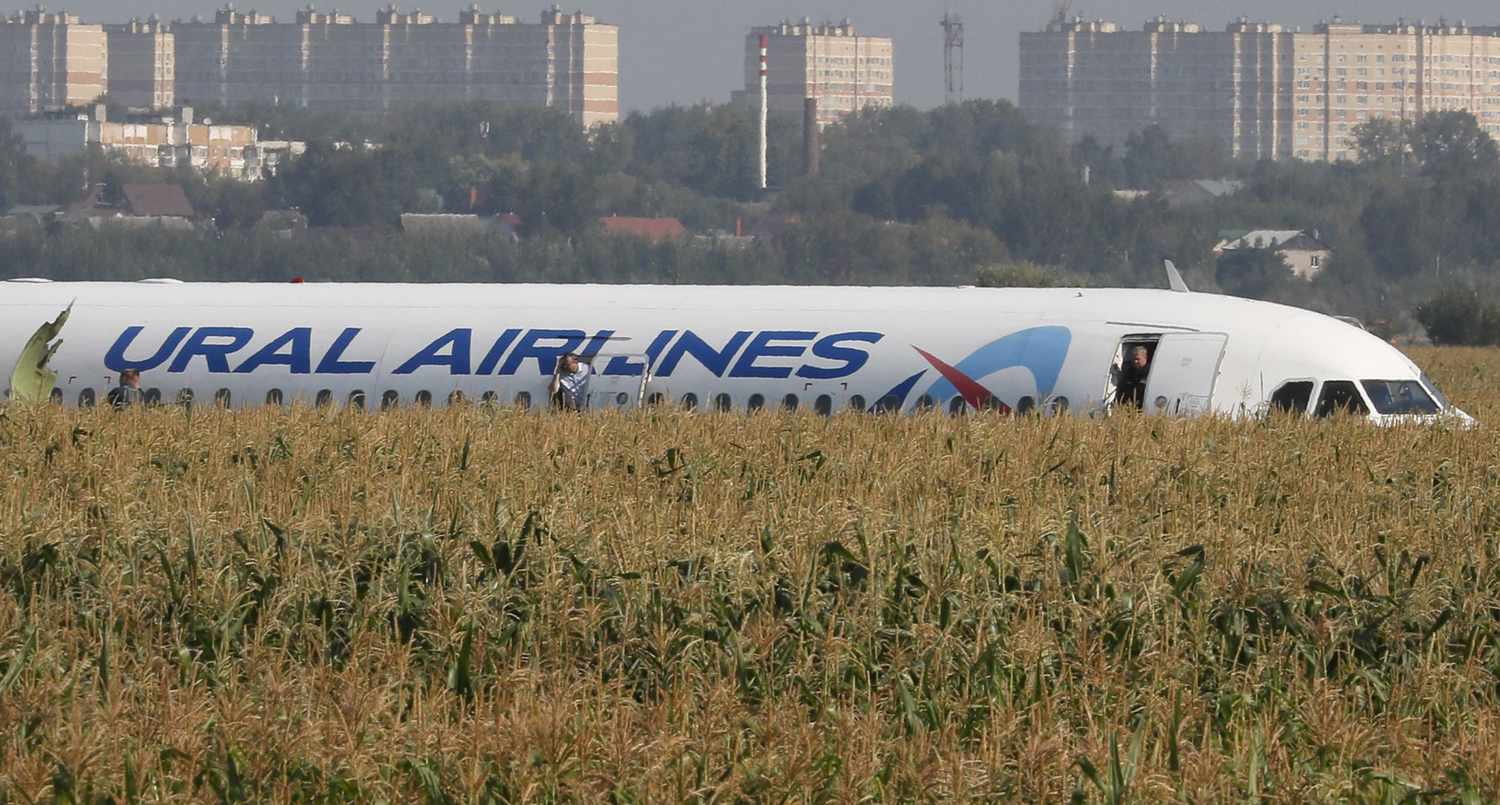 A handout still image taken from a video footage made available by the press service of the Moscow region branch of the Russian Emergency Situations Ministry shows passengers walking through the field after evacuation from the Ural Airlines A-321 passenger plane which made emergency landing outside Zhukovsky airport in Ramensky district of Moscow region 15 August 2019
