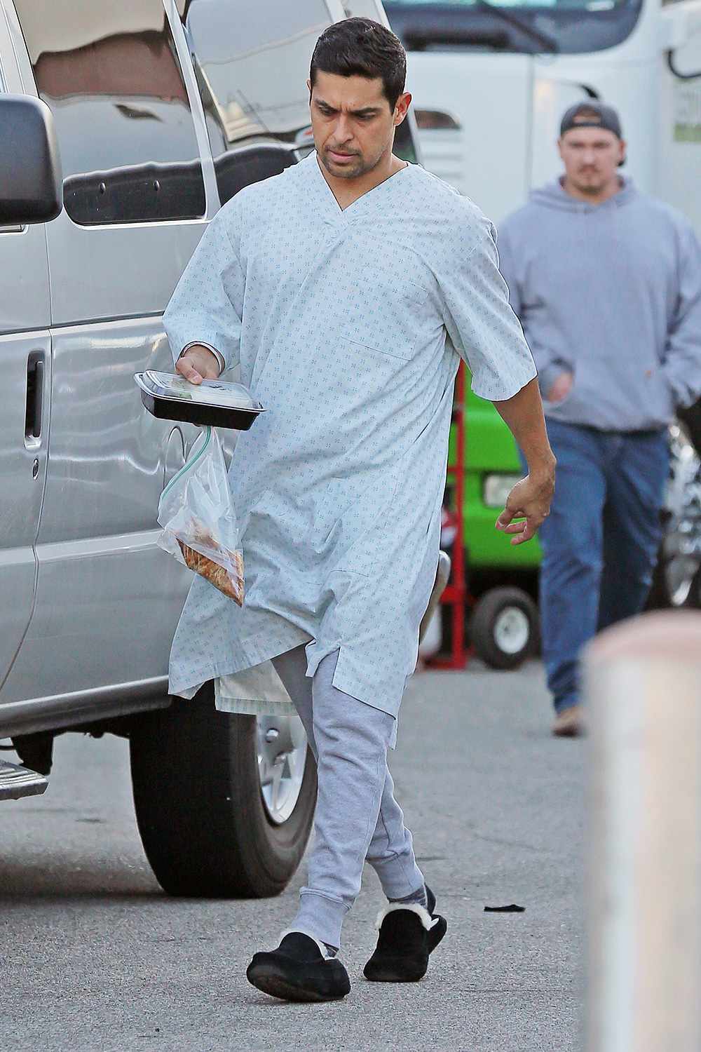 Wilmer Valderrama carried fried chicken while wearing a hospital patient gown as he walks around on the film set of NCIS in Los Angeles on Sunday