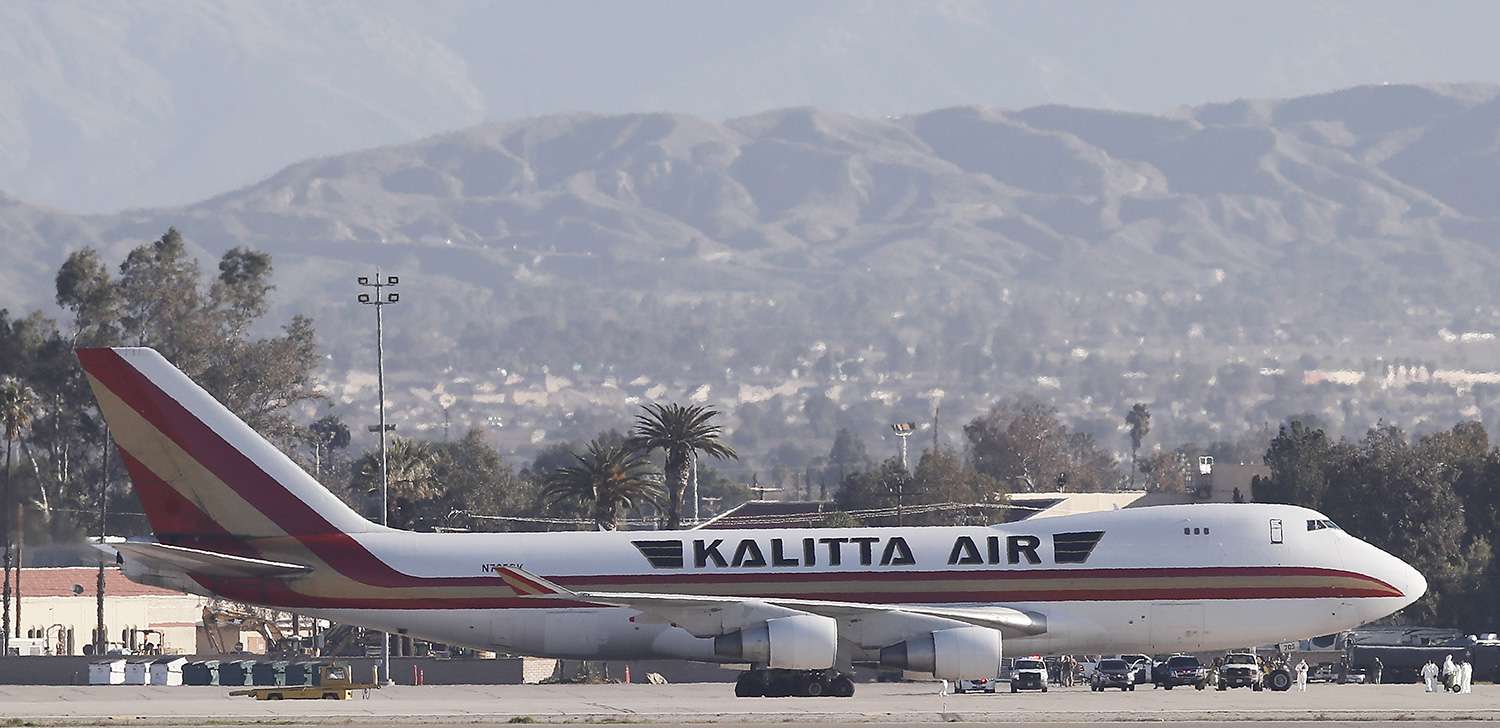 People in hazmat suits are seen outside of the Kalitta Air Boeing 747-400 freighter as buses approach the aircraft at the March Air Reserve Base carrying about 200 American evacuees in Riverside, California, USA, 29 January 2020