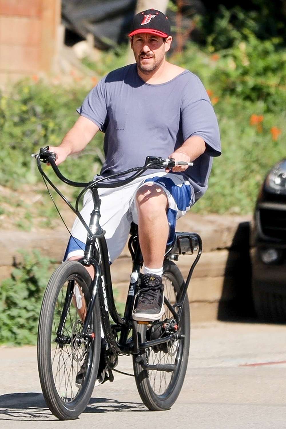Adam Sandler and his wife Jackie share a laugh as they race each other on cruisers while out for a bike ride