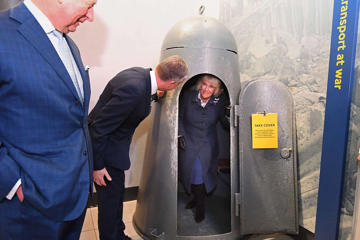 Prince Charles, Prince of Wales (L) reacts as Britain's Camilla, Duchess of Cornwall (C) tries out a one person air raid shelter during their visit to the London Transport Museum in London on March 4, 2020