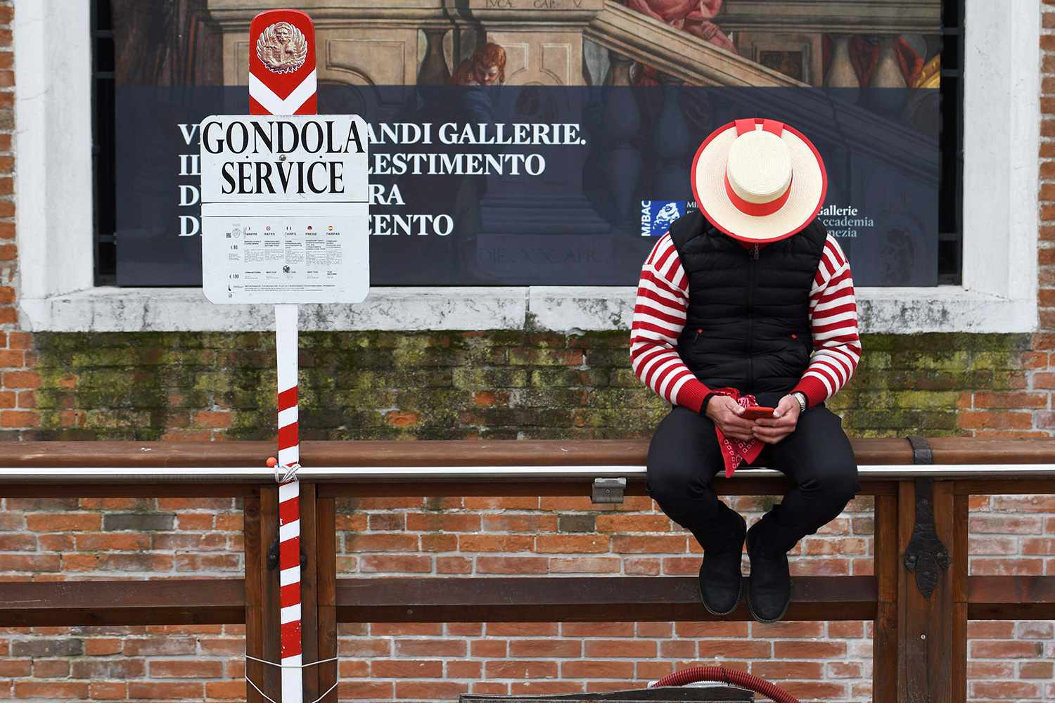 A Gondoliere checks his mobile phone while waiting for tourists in Venice on March 5, 2020