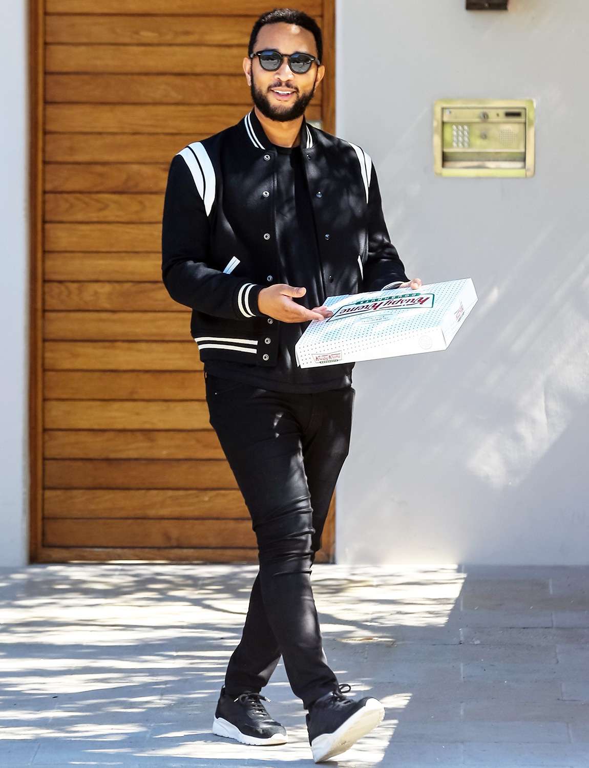 John Legend leaves Krispy Kreme donuts for the media as he and Chrissy Teigen leave their home in Malibu